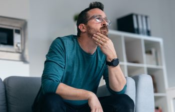 Shot of worried mature man thinking about what he has read on his mobile phone while sitting on the couch at home